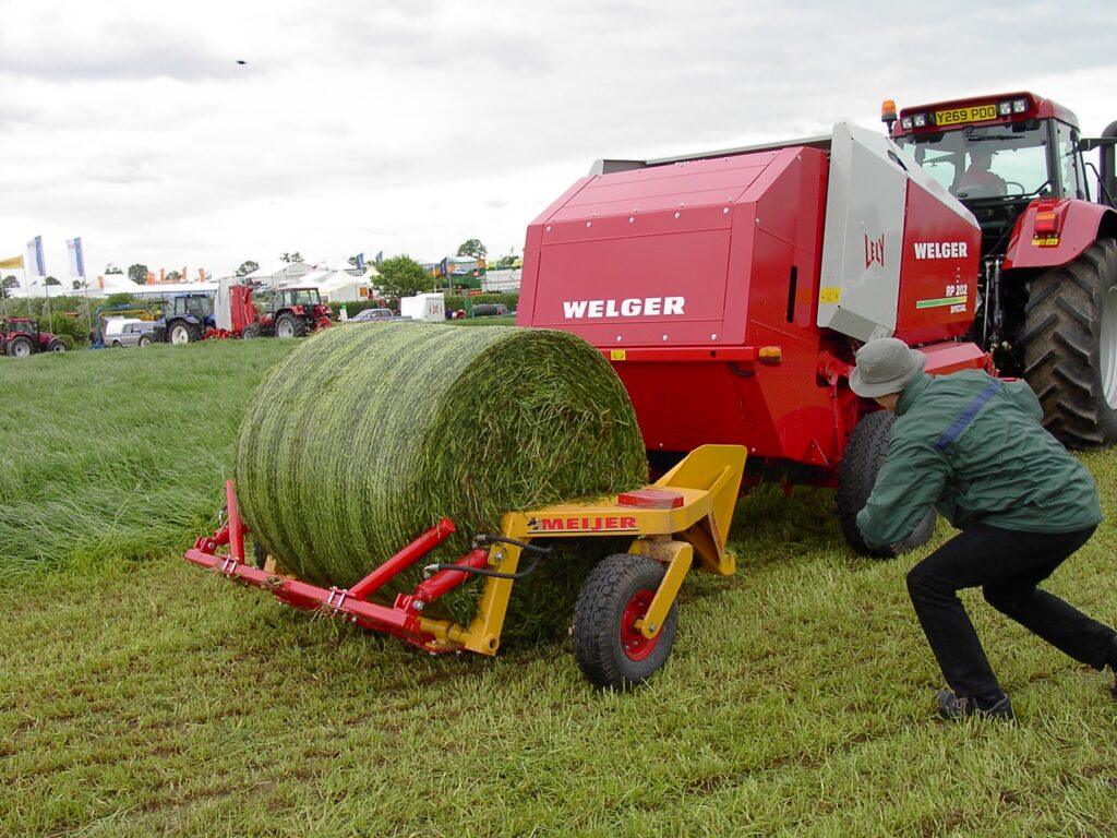 Ronde balenverzamelaar achter pers op het veld